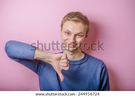 Handsome young man lowered his fist with the thumb down. Close portrait. disgruntled gesture.