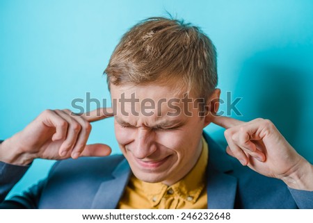 Closeup portrait young, angry, unhappy, stressed man covering his ears, looking up, to say, stop making loud noise it\'s giving headache. Negative emotions, face expressions