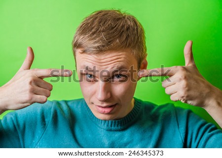 young man gesturing with fingers against his temple, are you crazy?