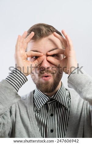 Serious man with hand over eyes, looking through fingers