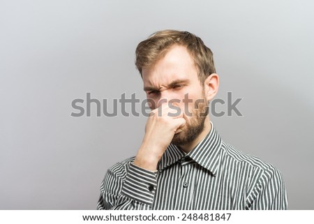 Closeup portrait of young man, disgust on face, pinches his nose, something stinks very bad smell, situation, asking is it you, isolated on gray background. Negative emotion facial expression feeling