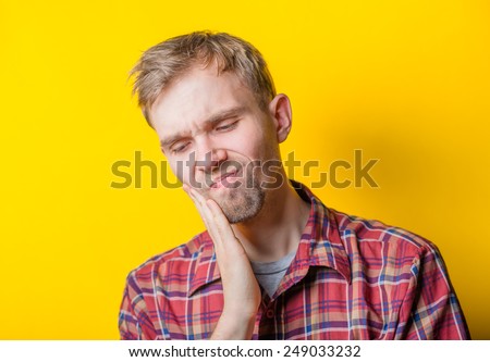 Young men in tooth pain isolated over yellow background