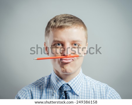 young funny man holding a pencil between the lip and nose