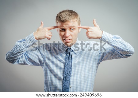 Game over! Frustrated mature man in shirt and tie gesturing handgun near head and looking at camera while standing against grey background