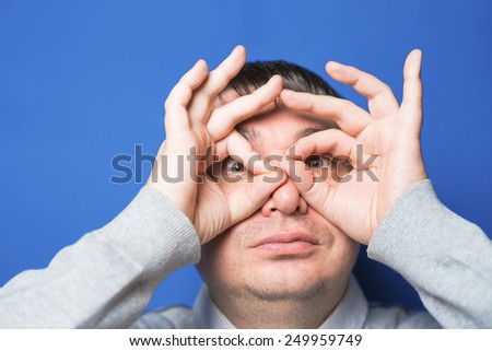 Funny young man with hand over eyes, looking through fingers