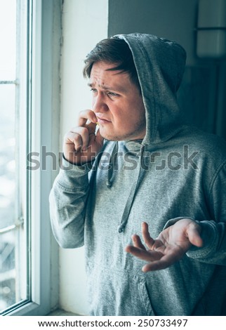 The hooded man talking on the phone at the window
