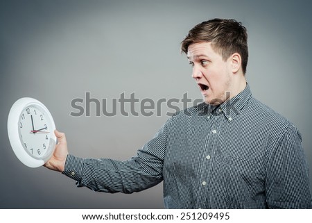 Closeup portrait of an busy schedule, unhappy male  holding big clock running out of time isolated on white background