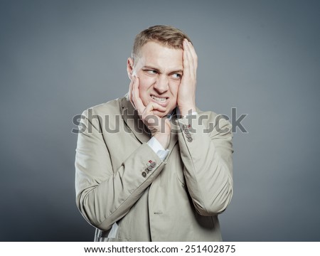 Expressions. Handsome young man in suit feeling fear with open mouth and closing eyes with hands