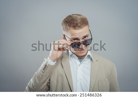 portrait of a young casual man taking his sunglasses off and looking at the camera