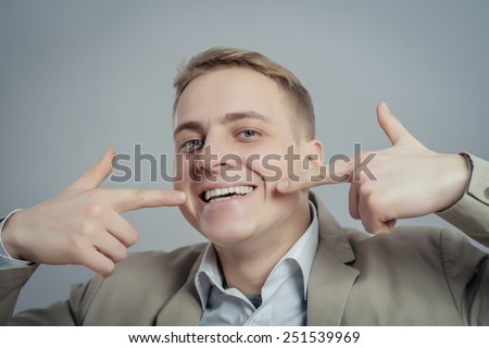 Portrait of handsome man pointing at his healthy smile or teeth