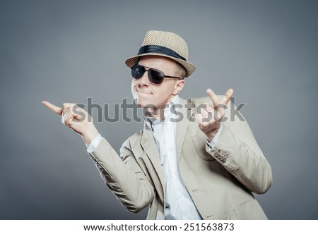Young dancing  businessman in elegant  suit, hat and sun glasses.