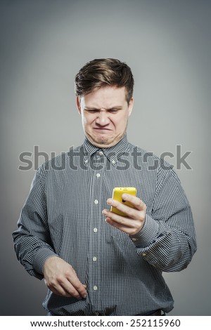 A confused young man looking at mobile phone