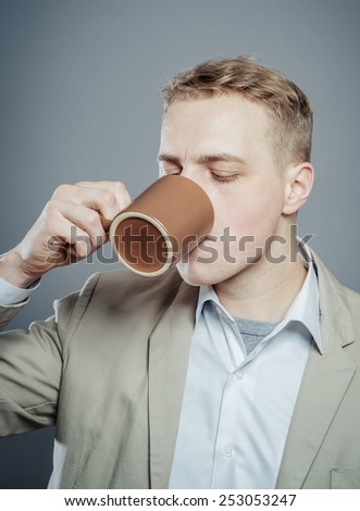 Portrait of handsome young man drink a cup tea, coffe, milk or other