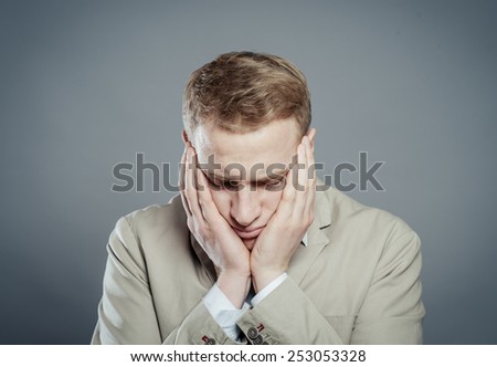 A young man close-up in a suit on a gray background, fall asleep, tired man,stressed and with headachetired man,stressed and with headache. The guy wants to sleep. Gesture. Photos