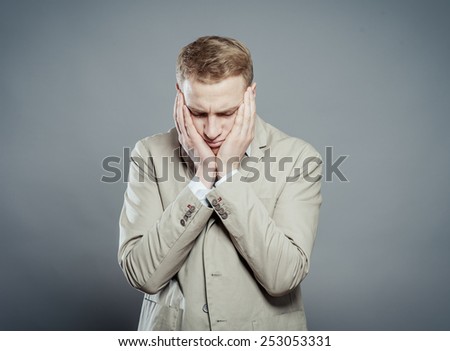 A young man close-up in a suit on a gray background, fall asleep, tired man,stressed and with headachetired man,stressed and with headache. The guy wants to sleep. Gesture. Photos