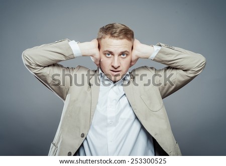 Annoyed businessman covering his ears with his hands, closing eyes.