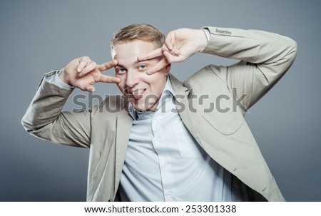 business man in a suit dancing, laughing and showing tongue giving the victory sign on eye