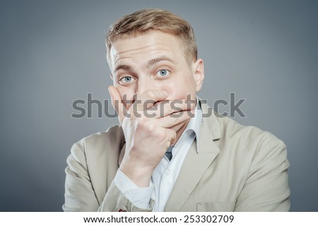 Business man covers his mouth with his hands, fear, does not want to roar, laughing