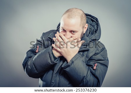 scared adult man with hand covering mouth and dramatic lighting