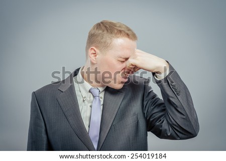 Young business man . Grabbing his nose with his fingers