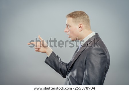 Closeup side view portrait of young man, laughing, pointing with finger at someone or something. Positive human face expressions, emotions, feelings, attitude, approach