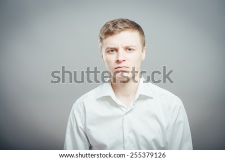 Portrait of serious offended man looking at camera over gray background