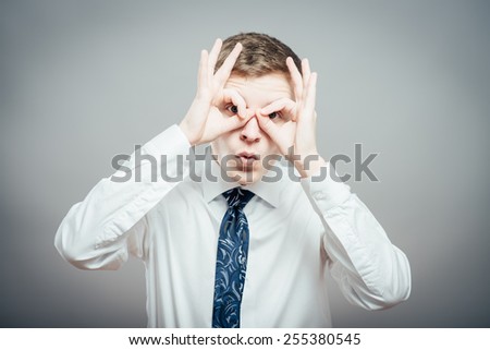 Portrait of young surprised man looking through his fingers like binoculars
