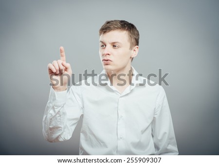 Handsome young man looking and pointing upwards