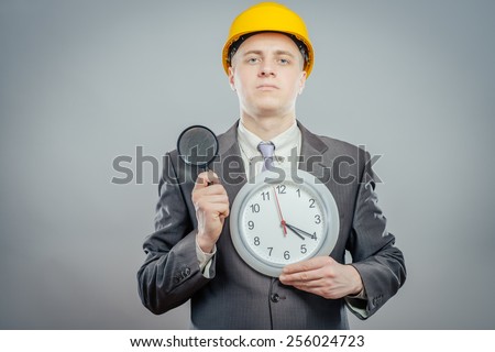 engineer man in helmet with a magnifying glass and big clock, it\'s time to inspection