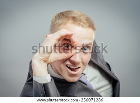 man with hand over eyes, looking through fingers