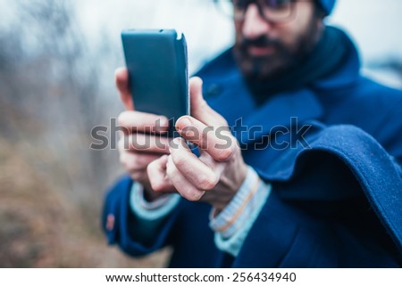 Adult man taking a picture with smart phone. Outdoor shot in nature.