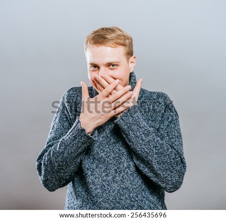 man covers his mouth with his hands, fear, does not want to roar, laughing