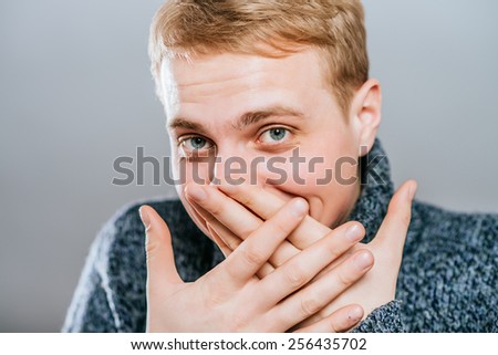man covers his mouth with his hands, fear, does not want to roar, laughing