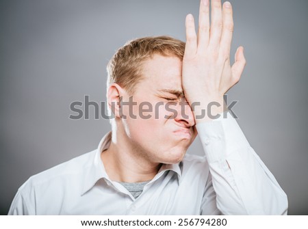 Frustrated man thinking deeply, hand on head.