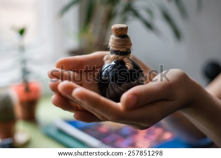hands holding a small black bottle with stopper