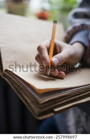 Human hands with pencil writing on paper