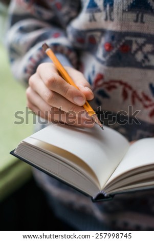 Human hands with pencil writing on paper