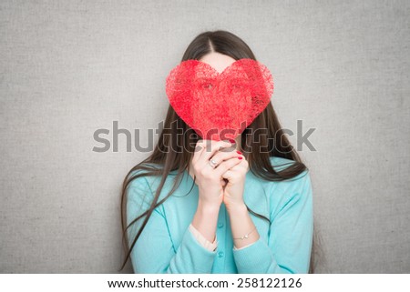 Young happy woman hold Love symbol red heart. Isolated on studio background female model.