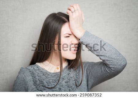 Closeup portrait headshot stressed sad young housewife, woman, employee having migraine, tension headache isolated on grey wall background. Human face expression emotion reaction, attitude