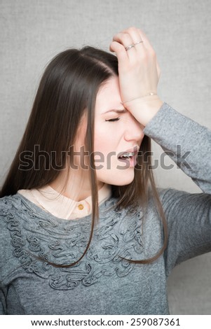 Closeup portrait headshot stressed sad young housewife, woman, employee having migraine, tension headache isolated on grey wall background. Human face expression emotion reaction, attitude