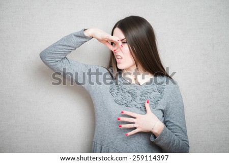 Closeup portrait middle aged woman who covers, pinches her nose with hand looks with disgust, something stinks, bad smell, situation. Human face expressions, body language