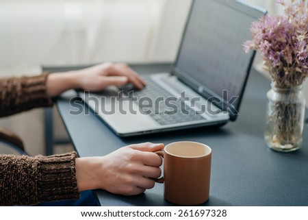 Office desk table with laptop computer, coffee cup and flower.
