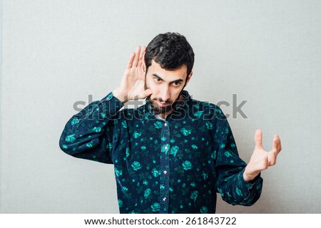 Young serious man   holding an ear to listen better, what you\'re saying. Photo Shoot.