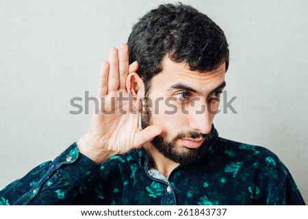 Young serious man   holding an ear to listen better, what you\'re saying. Photo Shoot.