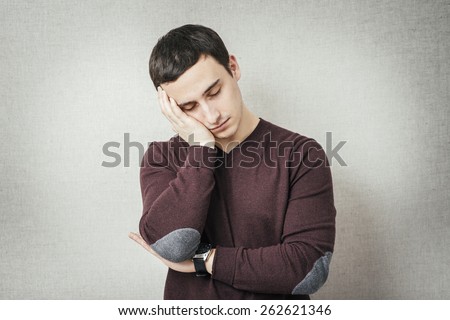Young Man wants to sleep. Put his head in his hands