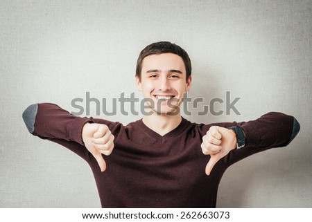 Young upset man showing thumbs down.