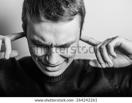 Blond young man shows he does not want to hear from you. Fingers in his ears. gesture. Close portrait.