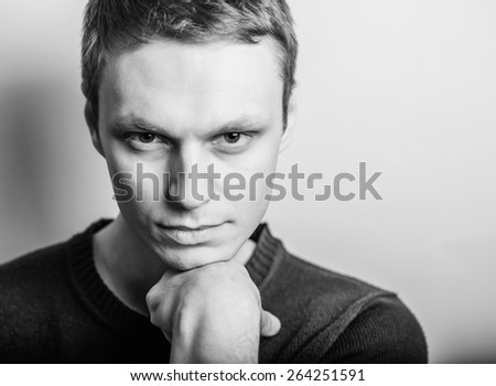 Blond young man thinks thinks. head resting on her hand, looking into the camera. Gesture.