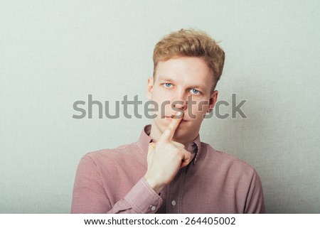 young man showing silence gesture, hand over mouth