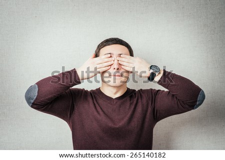 Portrait of a young man covering his eyes with hands